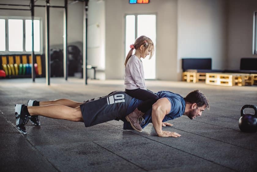 Dad exercising with daughter on his back